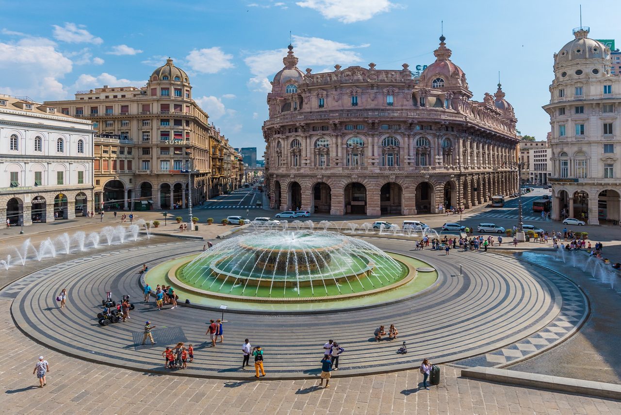 Piazza de Ferrari in Genoa, with its circular fountain in the foreground and grand historic buildings lining the square.